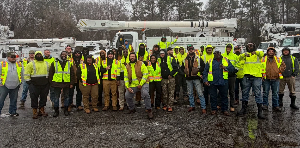 Entire Brothers in Linework crew standing together in front of bucket trucks, with every person visible